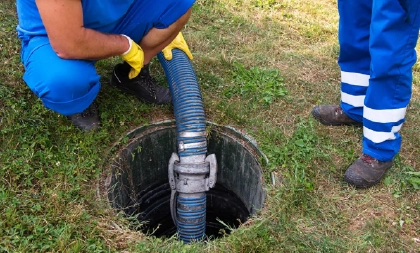Technicians in blue uniforms pumping a residential septic tank safely