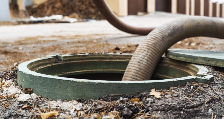 Industrial vacuum hose inserted into an open septic tank access port
